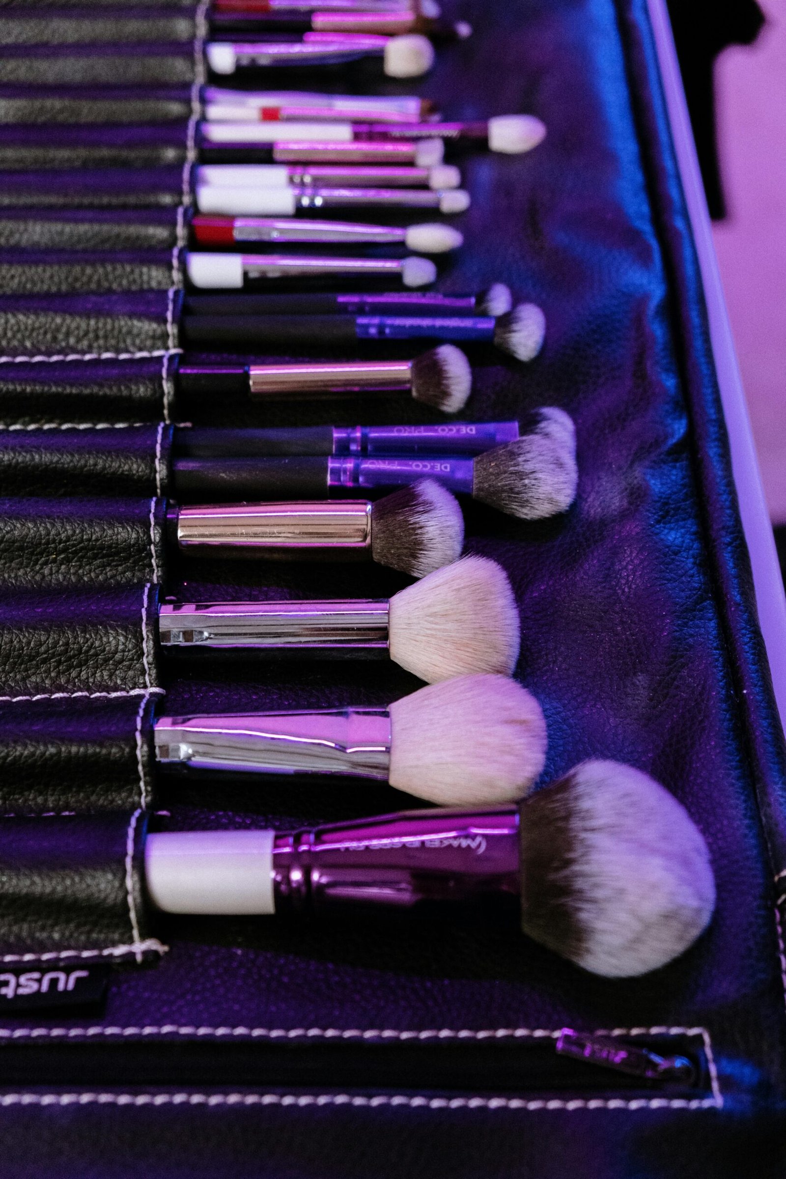 A set of professional makeup brushes neatly arranged in a leather holder, showcasing various types and sizes.